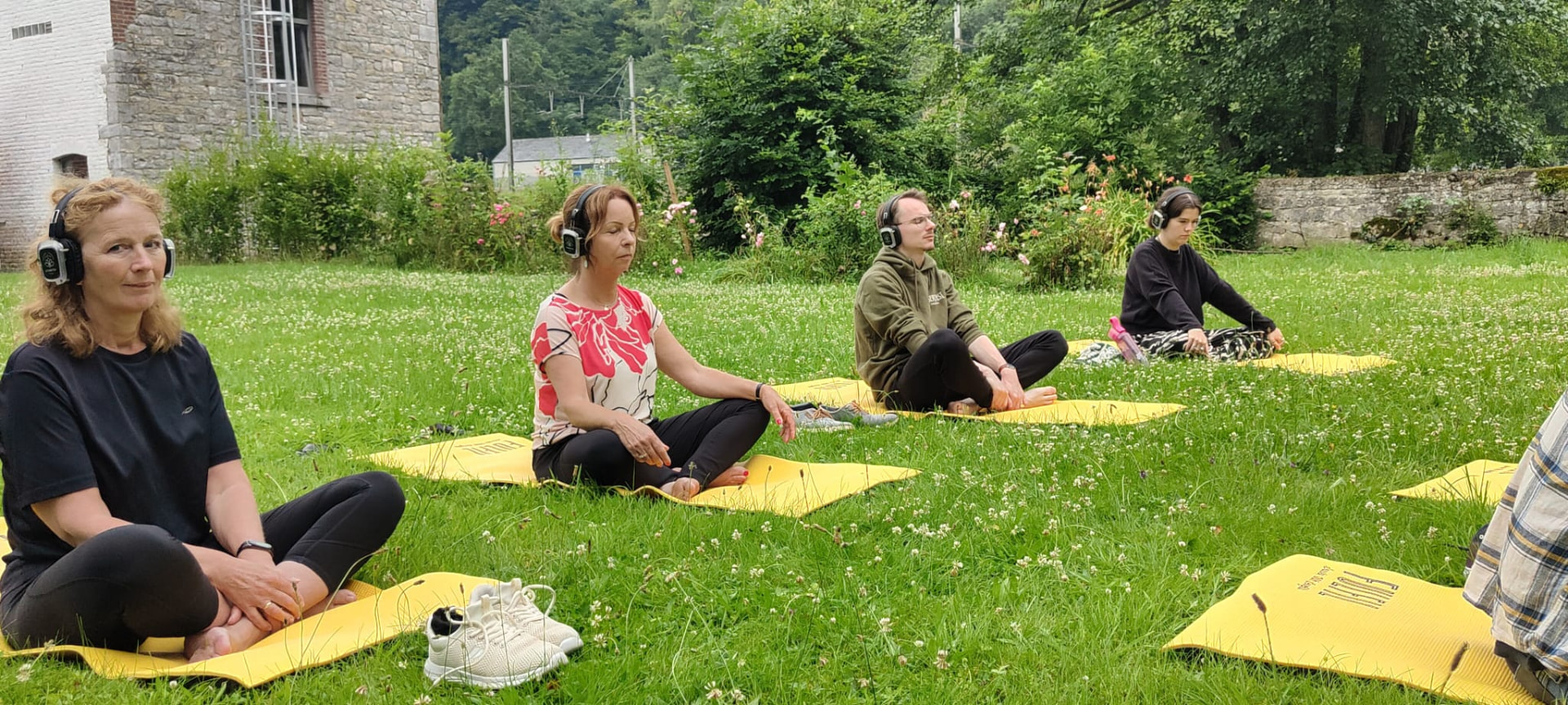 Deelnemers doen yoga op matten in het gras