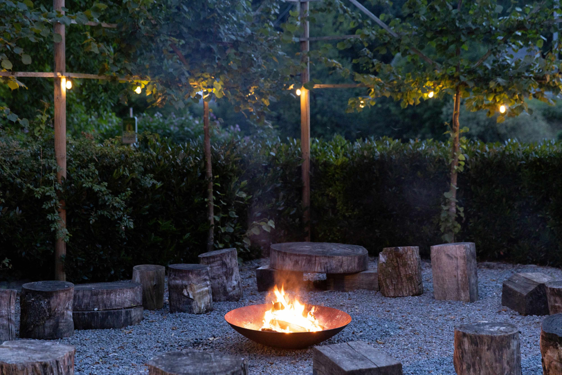 Het vuur brandt in de schaal tussen houten zitblokken in de tuin